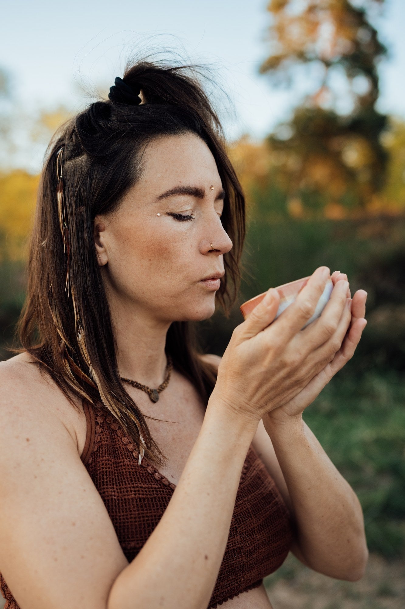 Frau hält eine Kakao-Schale und atmet tief ein, Ritual vor der Yogapraxis